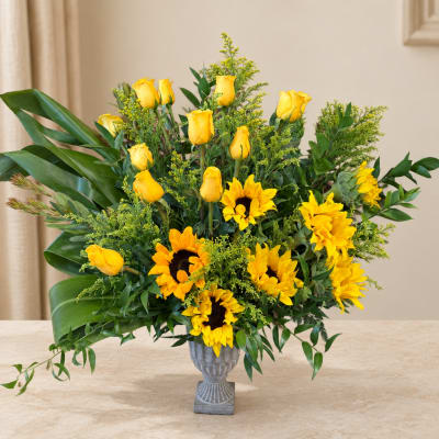 Yellow roses and sunflowers arranged in a gray vase