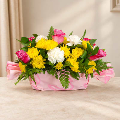 Pink roses and yellow chrysanthemums in a pink wrapped basket