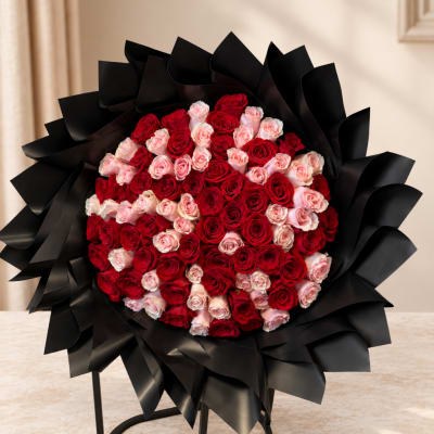 Large bouquet of red and pink roses wrapped in black paper