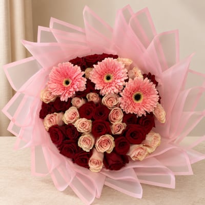 Bouquet of red and pink roses with three pink gerbera daisies