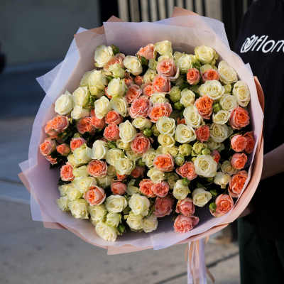 Large bouquet of cream and peach roses wrapped in pink paper