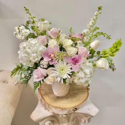 Pink and white roses with orchids and hydrangeas in a white vase