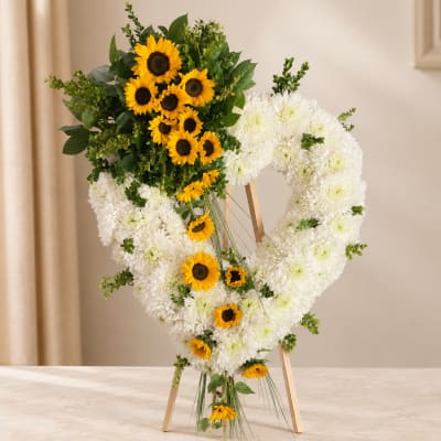 Heart-shaped floral wreath with white chrysanthemums and yellow sunflowers on an easel