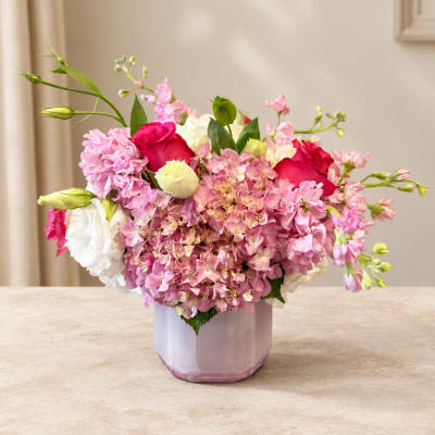 Pink and white floral arrangement in a lavender vase