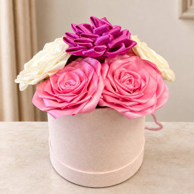 Pink and white ribbon roses arranged in a round hatbox
