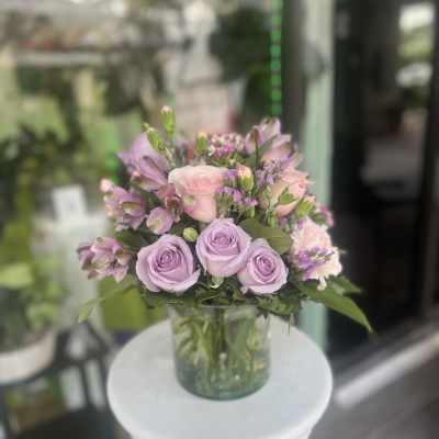Lavender and pink roses arranged in a clear glass vase