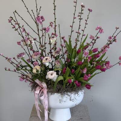 Pink blossoms and tulips in a white pedestal vase