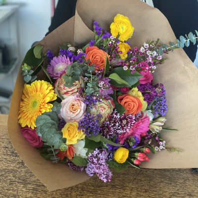 Mixed bouquet of colorful flowers wrapped in brown paper