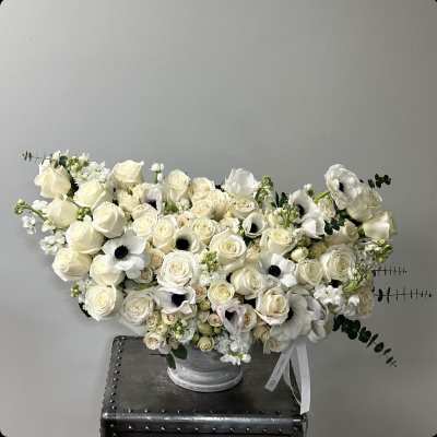 Cream rose arrangement with white anemones in a silver vase