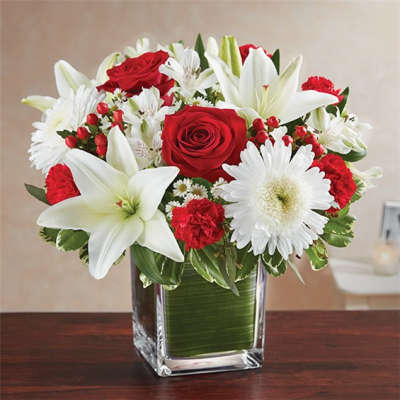 Red roses and white lilies in a clear square vase