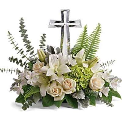 White lilies and cream roses arranged around a silver cross
