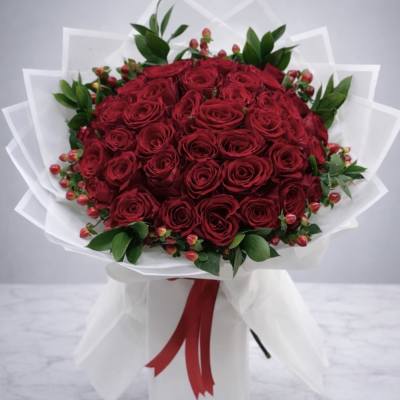 Bouquet of red roses wrapped in white paper with a red ribbon