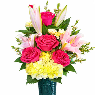 Pink roses and lilies in a teal vase with yellow hydrangeas