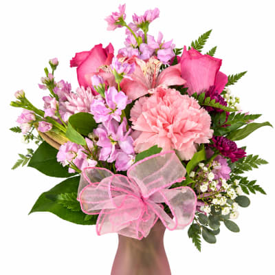Pink mixed flower bouquet in a matte pink vase with a sheer ribbon bow