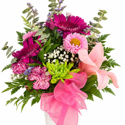 Pink and magenta mixed bouquet in a white vase with a large pink ribbon