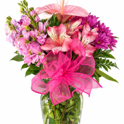 Pink and purple mixed bouquet in a glass vase with a bright pink bow