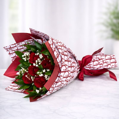 Bouquet of red roses wrapped in patterned paper with a red ribbon