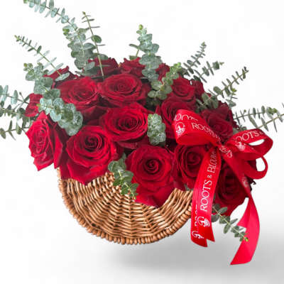Red roses in a wicker basket with eucalyptus and a red ribbon