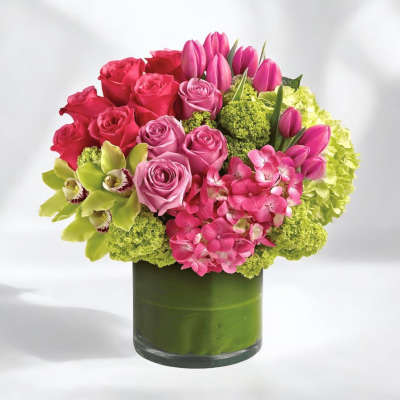 Pink roses and tulips arranged in a green glass vase