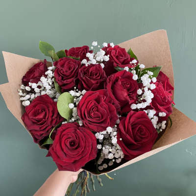 Bouquet of red roses with white baby's breath in brown paper