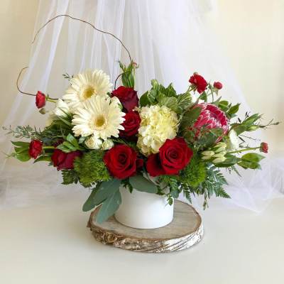 Red roses and white daisies arranged in a white vase