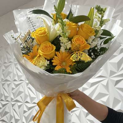 Yellow rose bouquet with lilies and gerbera daisies wrapped in white paper