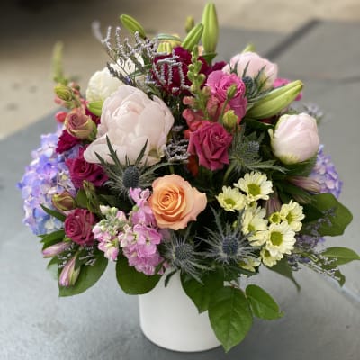 Mixed bouquet of pink, white, and peach flowers in a white vase