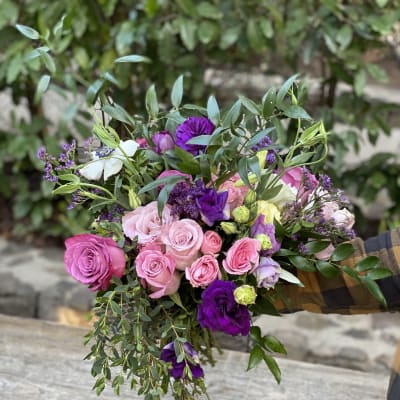 Hand-tied bouquet of pink and purple roses with greenery