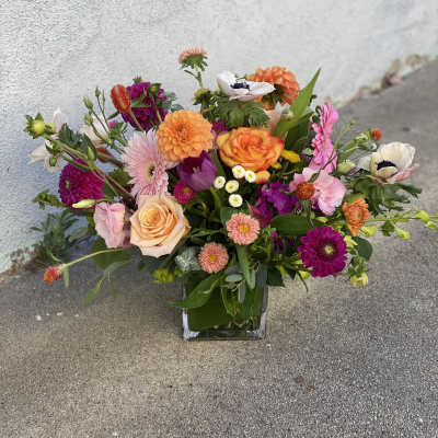 Mixed bouquet of colorful flowers in a square glass vase