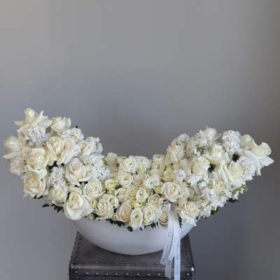 Large white rose arrangement in a white bowl vase