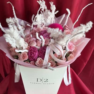 Pink roses and peonies in a white gift box with white decorative branches