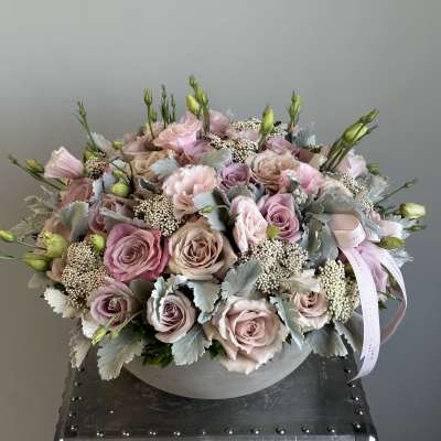 Round bouquet of blush roses and pale pink blooms in a gray box