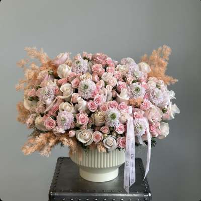 Large pastel rose arrangement in a white pedestal vase