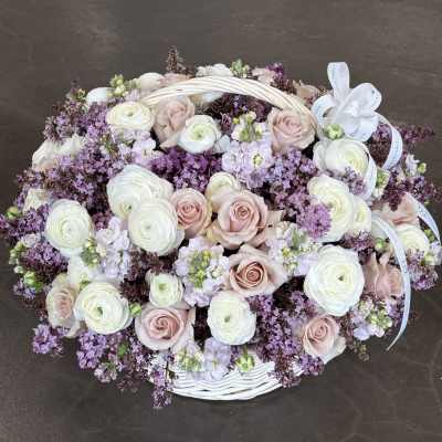 Oval basket arrangement of pale pink roses and white ranunculus with lavender filler
