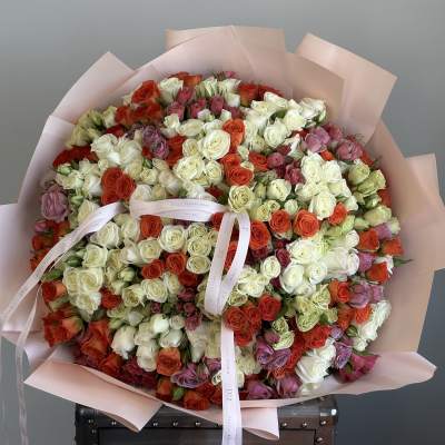 Large bouquet of multicolored roses wrapped in pale pink paper