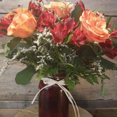 Bouquet of peach roses and red alstroemeria in a dark vase