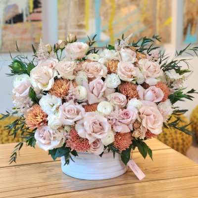 Blush rose and chrysanthemum arrangement in a white vase