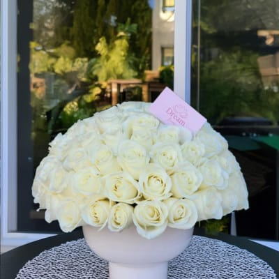 Large bouquet of white roses in a pale pink vase
