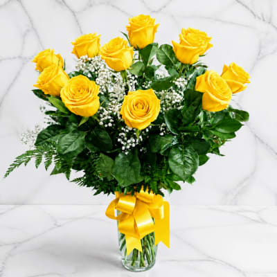 Yellow roses in a glass vase with a yellow ribbon