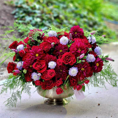 Red and pink flower arrangement in a gold pedestal vase