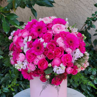 Pink bouquet of roses, ranunculus, and gerbera daisies in a pale pink box