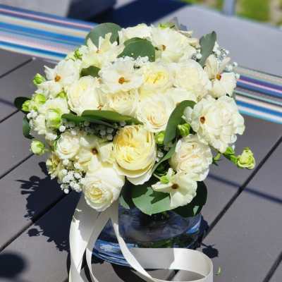 White floral bouquet in a glass vase with a white ribbon