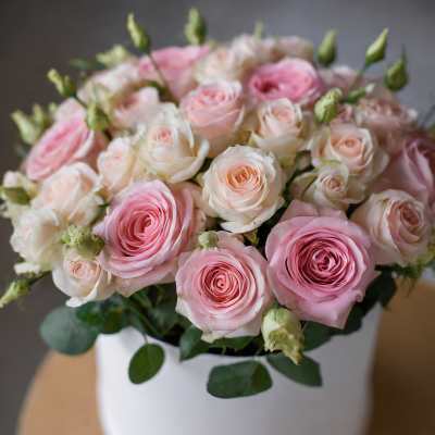 Pink and white roses arranged in a white hat box