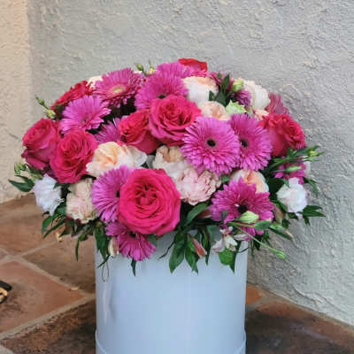 Pink roses and gerbera daisies arranged in a white hat box