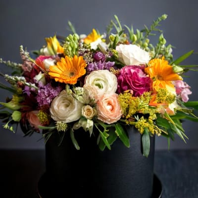 Mixed bouquet in a black hatbox with orange, white, pink, and purple flowers