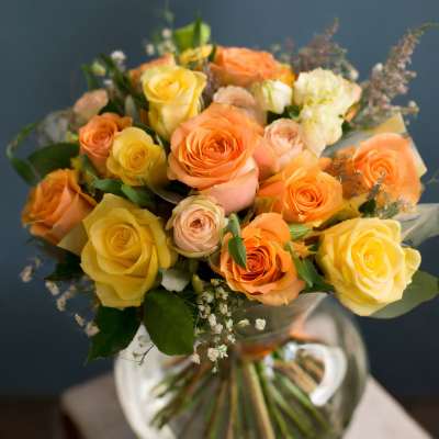 Bouquet of yellow and peach roses in a clear glass vase