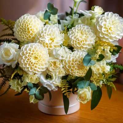 Cream-colored dahlia and rose arrangement in a white vase