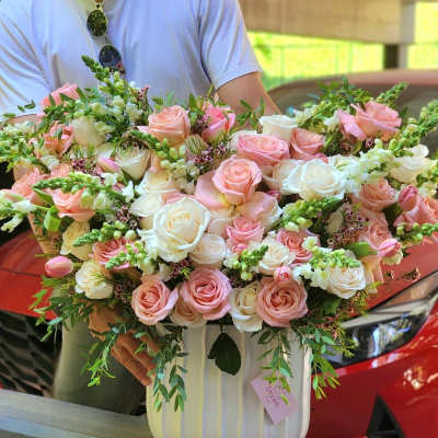 Large bouquet of pink and white roses in a striped box