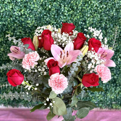 Bouquet of red roses, pink lilies, and carnations in a white vase