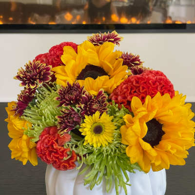 Sunflowers and mixed chrysanthemums arranged in a white pumpkin vase